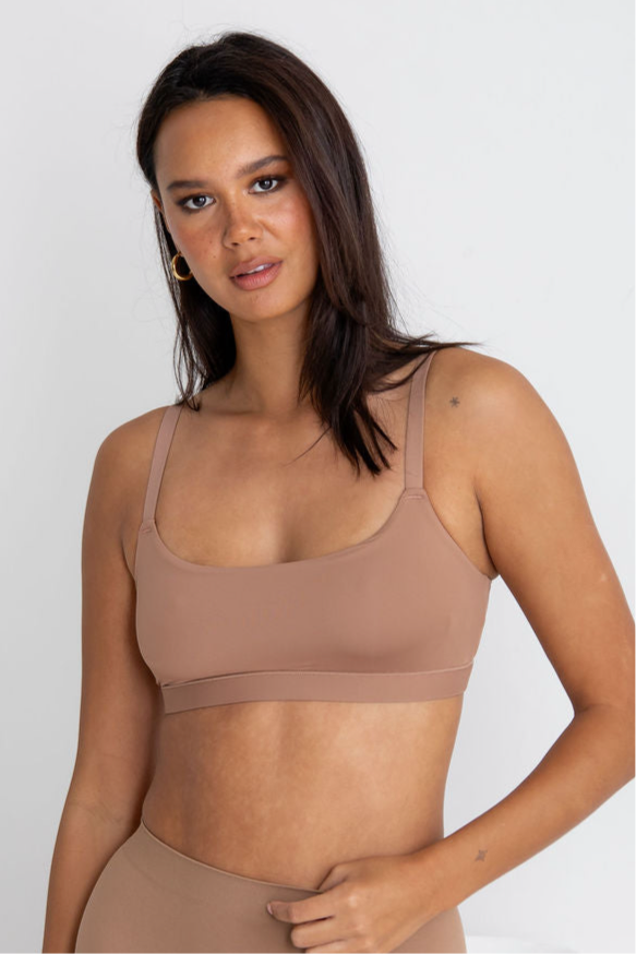 Woman wearing a beige sports bra and leggings against a white background