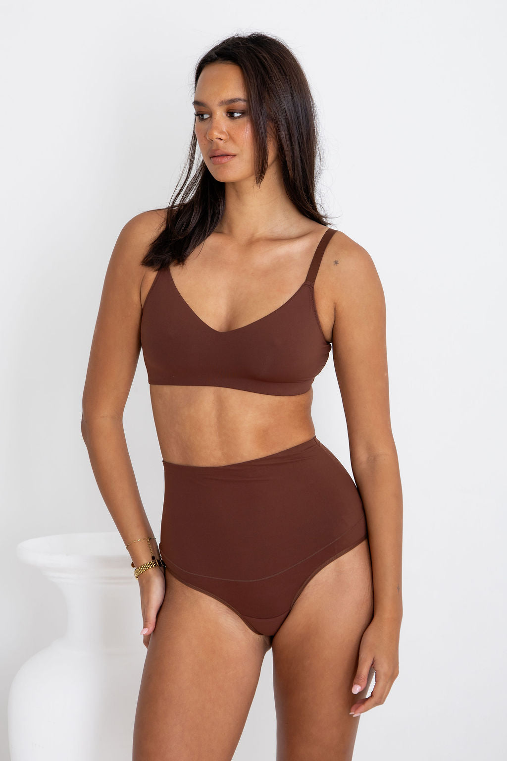 Woman wearing a brown bikini set against a white background