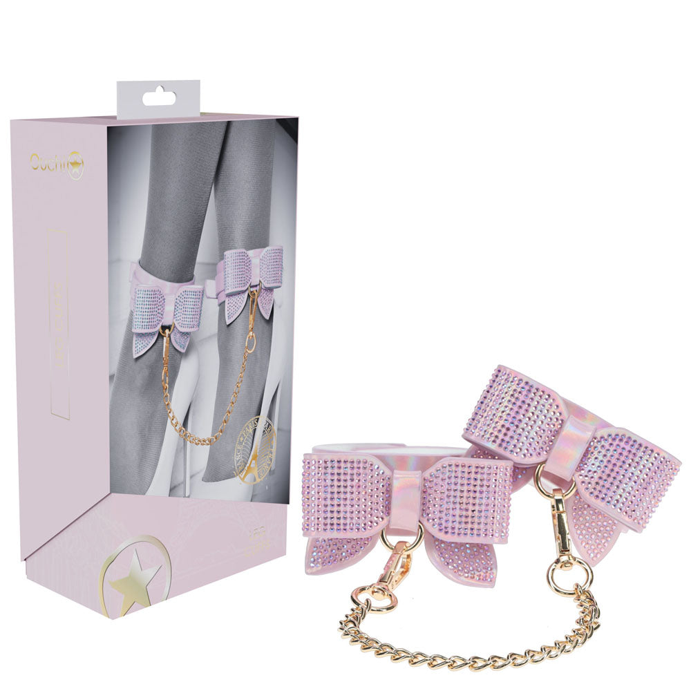 Pink leg collar with bow and chain next to its packaging on a white background