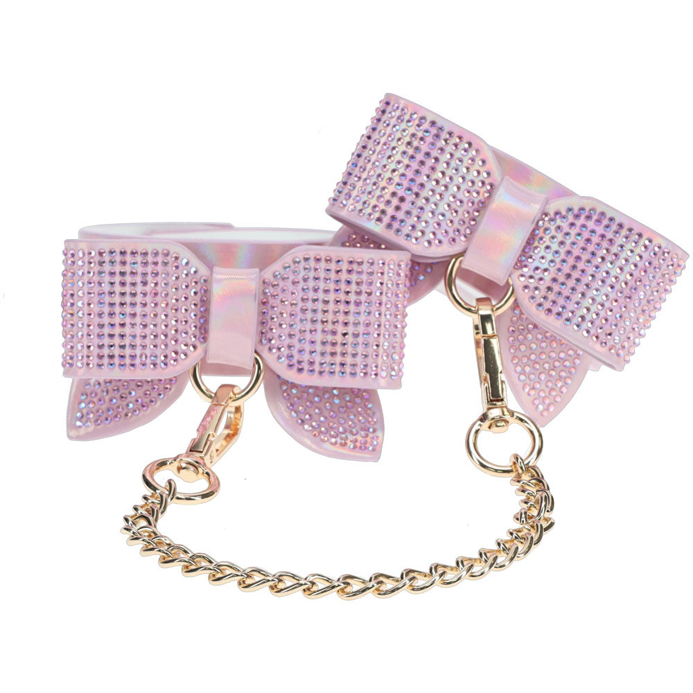 Pink bow with rhinestones and a gold chain on a white background