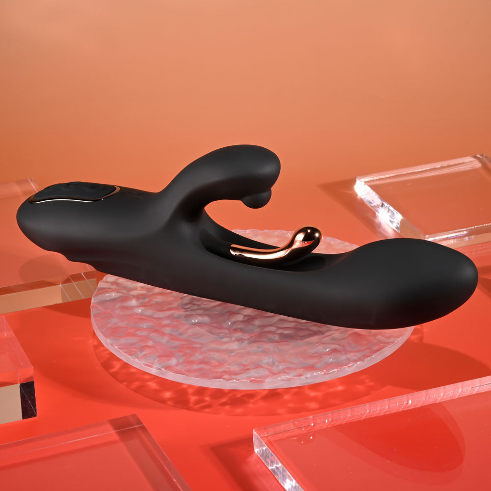 Black and gold electronic device on a clear stand with an orange background
