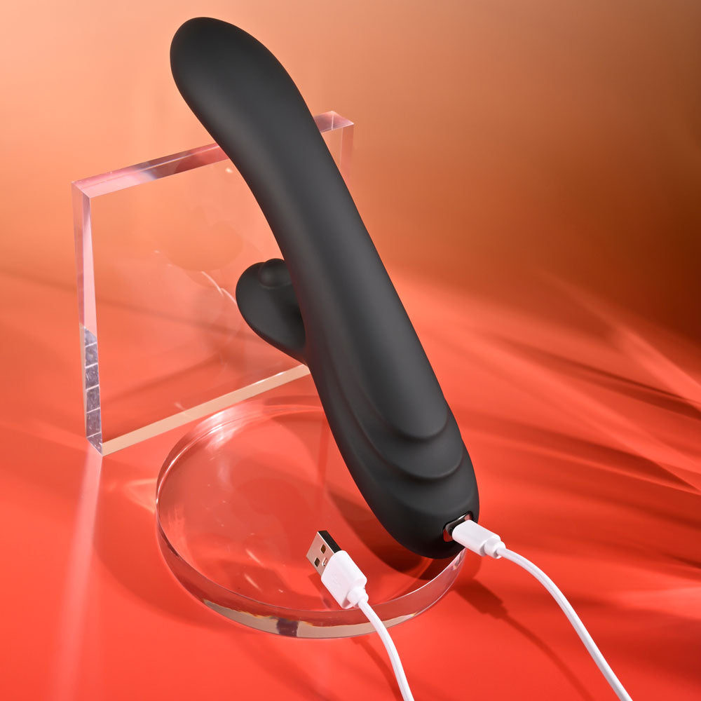 Black handheld electronic device on a clear stand with USB cables on an orange background