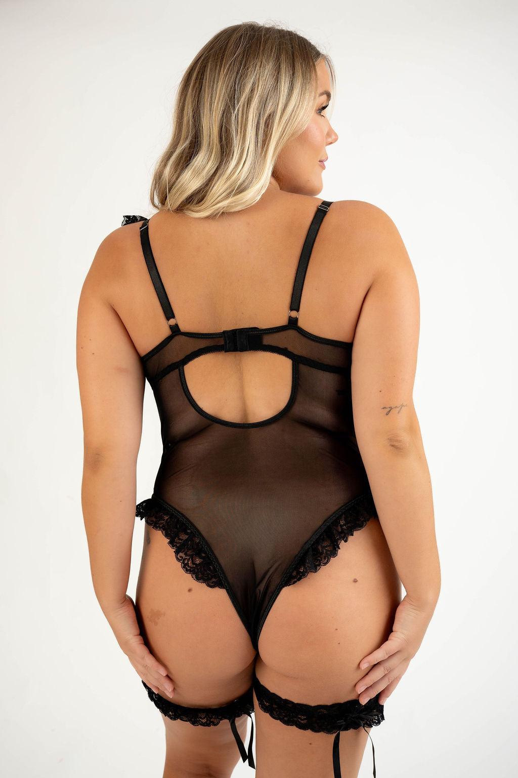 Woman wearing a black lace lingerie set on a white background